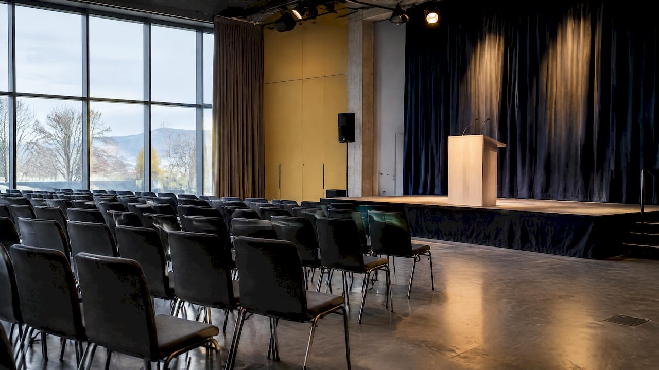 Scène de conférence éclairée par une fenêtre en arrière-plan et un projecteur